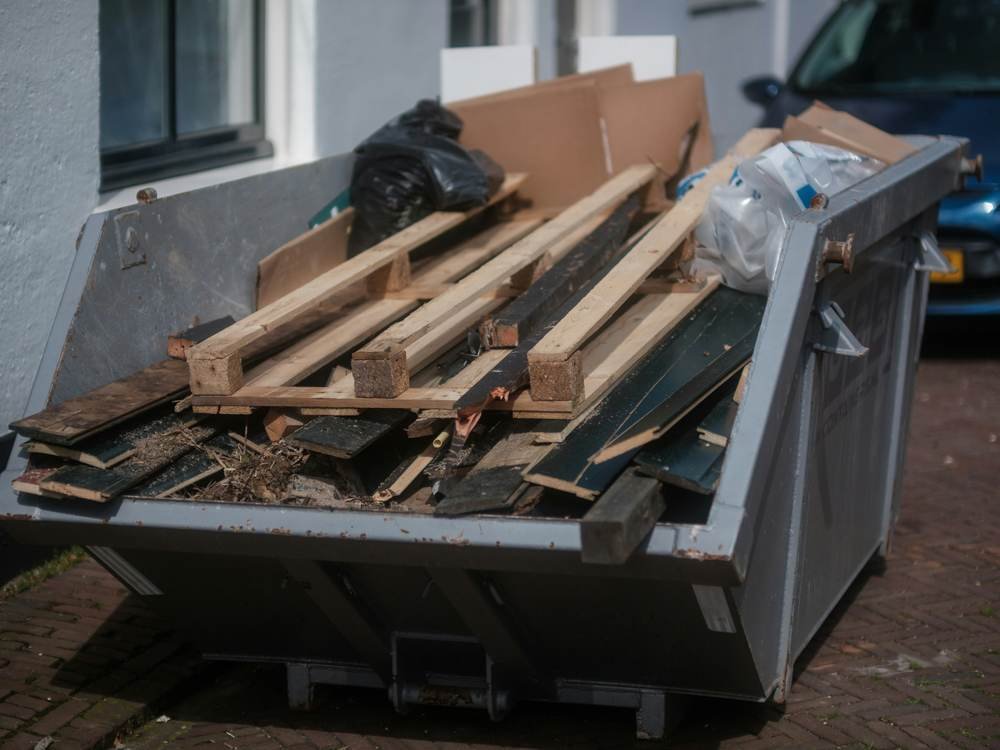 Junk removal skip filled with wood, cardboard and household debris